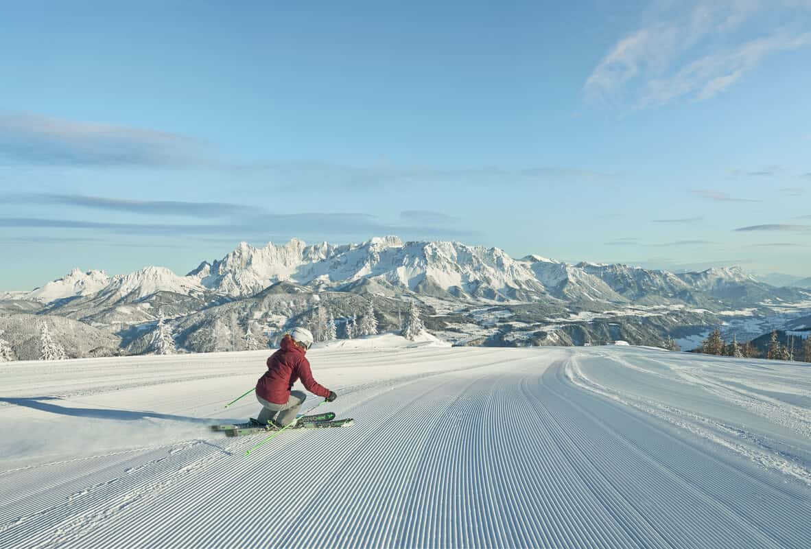 Skifahrerin am frühen Morgen auf frisch präparierter Piste der Reiteralm mit Blick auf das Dachsteinmassiv