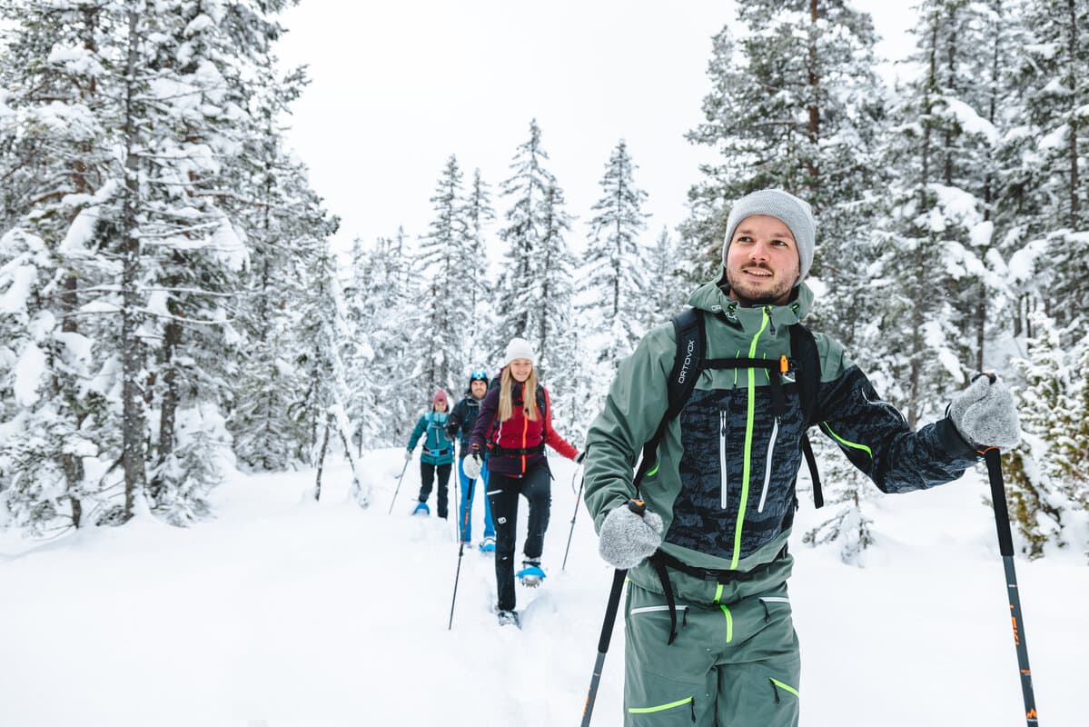 Kleine Wandergruppe beim Winterwandern durch den tief verschneiten Wald bei Schladming